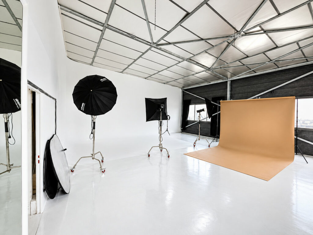 Plateau du studio Muze à Ivry-sur-Seine : sol blanc, verrière, flashs et fond papier camel